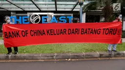 Aktivis WALHI bertopeng orangutan membentangkan spanduk tuntutan saat menggelar aksi di depan Gedung Bank of China, Jakarta, Jumat (1/3). Aksi ini digelar karena izin lingkungan PLTA Batang Toru dianggap cacat. (Liputan6.com/Fery Pradolo)