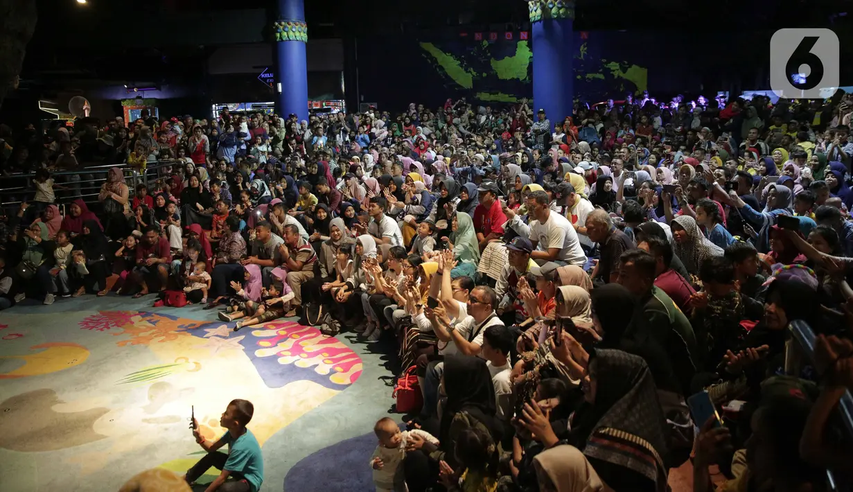 Pengunjung menyaksikan Sinterklas bersama para kurcaci menyuguhkan atraksi di Sharkquarium arena Sea World Ancol, Jakarta, Rabu  (25/12/2019). Sea World Ancol menampilkan atraksi penyelam Scuba Santa pada perayaan Natal 2019. (Liputan6.com/Faizal Fanani)