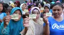 Warga menunjukkan kupon yang akan ditukarkan dengan paket sembako murah dari Indosiar di Joglo, Jakarta, Senin (13/6). Paket berisikan 5 kg beras, 2 liter minyak goreng, 1 kg gula pasir dan 1 kg tepung terigu dijual Rp 30 ribu‎ (Liputan6.com/Angga Yuniar)