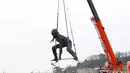 Patung perunggu terbesar di Inggris,  berjudul 'Messenger' tiba dengan tongkang di pesisir pantai Plymouth, Senin (18/3). Patung itu mengambarkan seorang wanita dengan tinggi 7m dan lebar 9m dalam posisi berjongkok. (REUTERS/Peter Nicholls)
