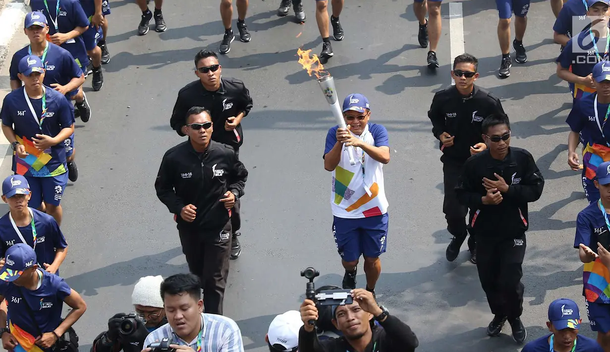 Pelari membawa obor Asian Games 2018 dalam Torch Relay Asian Games 2018 di kawasan TMII, Jakarta Timur, Rabu (15/8). Kota Jakarta menjadi persinggahan terakhir api Asian Games yang dimulai dari wilayah Jaktim dan Jaksel. (Liputan6.com/Immanuel Antonius)