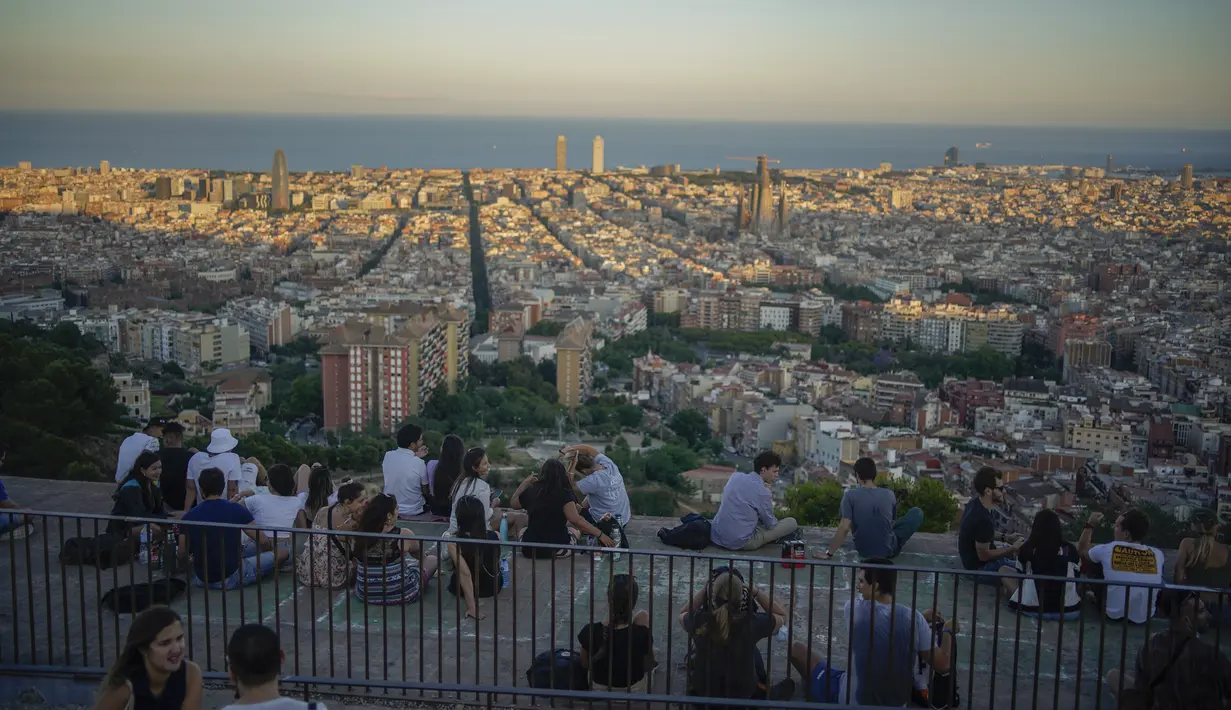 Orang-orang duduk di sudut pandang panorama kota Barcelona, Spanyol, Senin (21/10/2021). Barcelona adalah sebuah kota terbesar kedua di Spanyol dan merupakan ibu kota wilayah otonom Katalonia. (AP Photo/Joan Mateu)