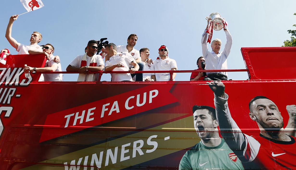 Pelatih Arsenal, Arsene Wenger (kanan) mengangkat trofi Piala FA saat parade kemenangan di London, Inggris, (18/5/2014). (REUTERS/Andrew Winning)