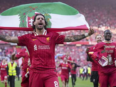 Pemain Liverpool, Dominik Szoboszlai melakukan selebrasi dengan membawa bendera Hungaria setelah membawa timnya memastikan gelar juara Liga Inggris 2024/2025 di Anfield, Liverpool, Inggris, Minggu (27/04/2025) waktu setempat. (AP Photo/Jon Super)