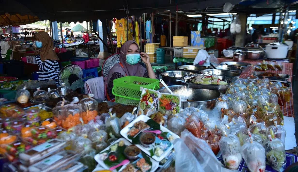Seorang pedagang melihat sambil mengenakan masker di pasar, sebagai bagian dari upaya untuk menghentikan penyebaran virus corona Covid-19, selama bulan suci Ramadhan di provinsi selatan Thailand, Narathiwat (17/4/2021). (AFP/Madaree Tohlala)