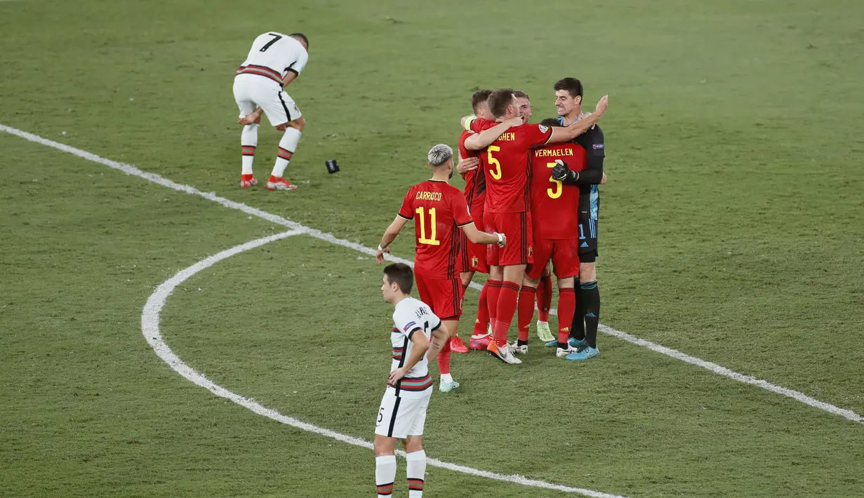 Para pemain Belgia merayakan kemenangan saat kapten Portugal Cristiano Ronaldo (7) bereaksi setelah babak 16 besar Euro 2020 di Estadio La Cartuja, Sevilla, Spanyol, Senin (28/6/2021) dini hari WIB. Ronaldo membuang dan menendang ban kapten usai kalah dari Belgia 0-1. (Jose Manuel Vidal/Pool via AP)