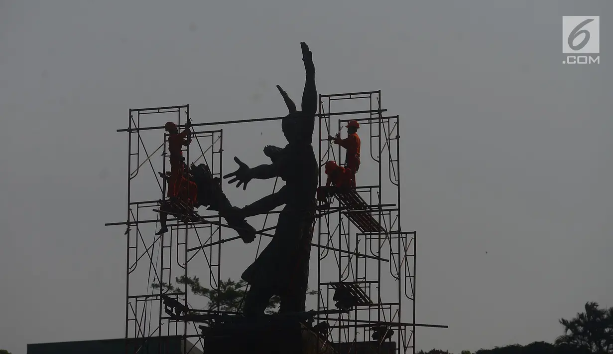 Pekerja memasang rangka besi untuk membersihkan Patung Selamat Datang di Bundaran HI, Jakarta, Sabtu (4/8). Patung Selamat Datang dibersihkan untuk perhelatan Asian Games 2018 yang akan berlangsung pertengahan Agustus bulan ini. (Merdeka.com/Imam Buhori)