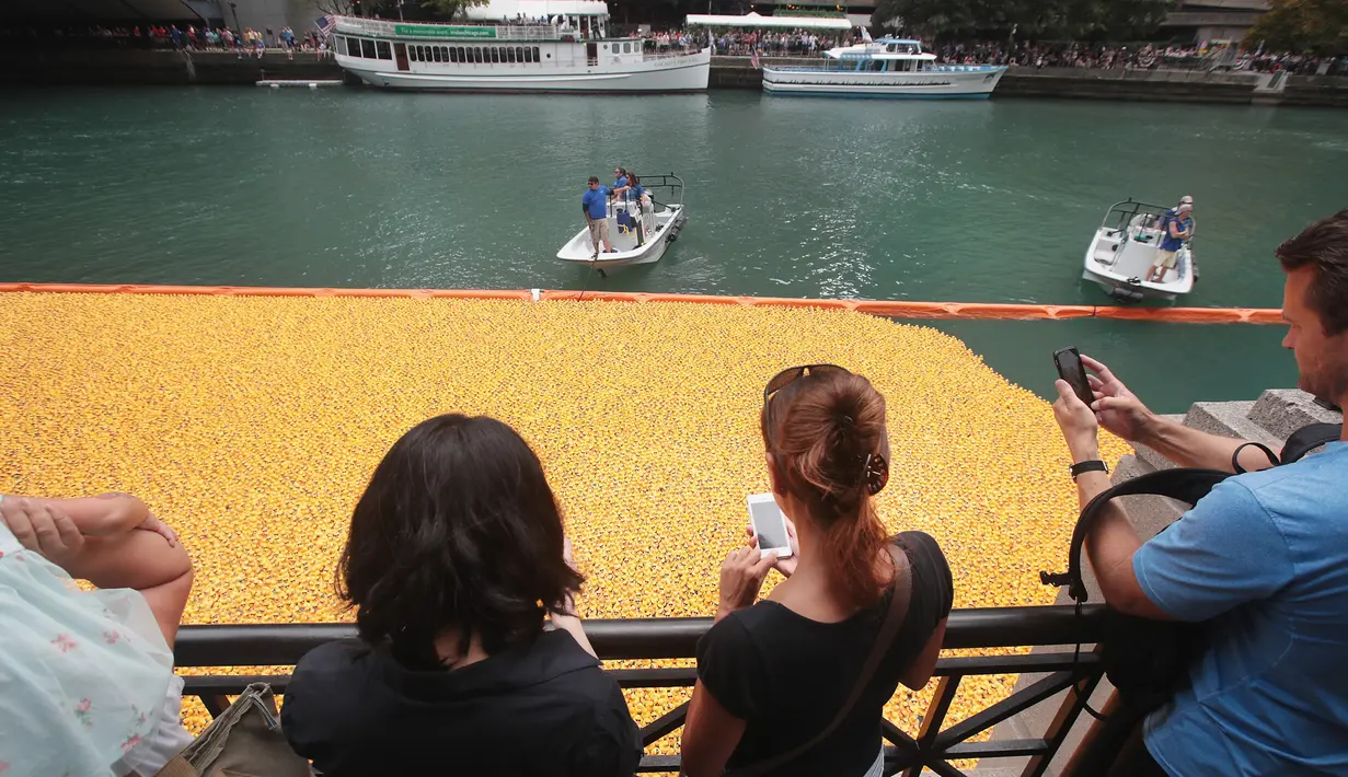 Penonton menyaksikan Bebek Karet melintasi Sungai Chicago selama Windy City Rubber Ducky Derby, Chicago, Illinois (3/8). 60.000 bebek karet memulai balapan yang mengumpulkan sekitar $ 350.000 untuk Olimpiade Khusus Illinois. (Scott Olson/GettyImages/AFP)