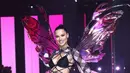 Ibu tiga anak, Adriana Lima tampil bersinar  memadukan bikini hitamnya dengan long pants dan cut out long sleeve top motif kotak-kotak. Ia melengkapi penampilannya dengan sayap hologram. [@runway.dolls].