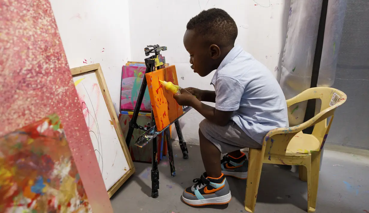 Ace-Liam Nana Sam Ankrah, yang akan berulang tahun ke dua pada bulan Juli, memamerkan tabung catnya di galeri seni ibunya di Accra, Ghana, pada 27 Mei 2024. (AP Photo/Misper Apawu)
