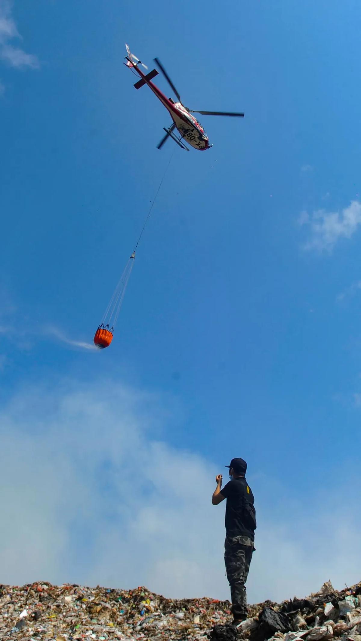 Helikopter water bombing BNPB menjatuhkan air saat melakukan pemadaman.