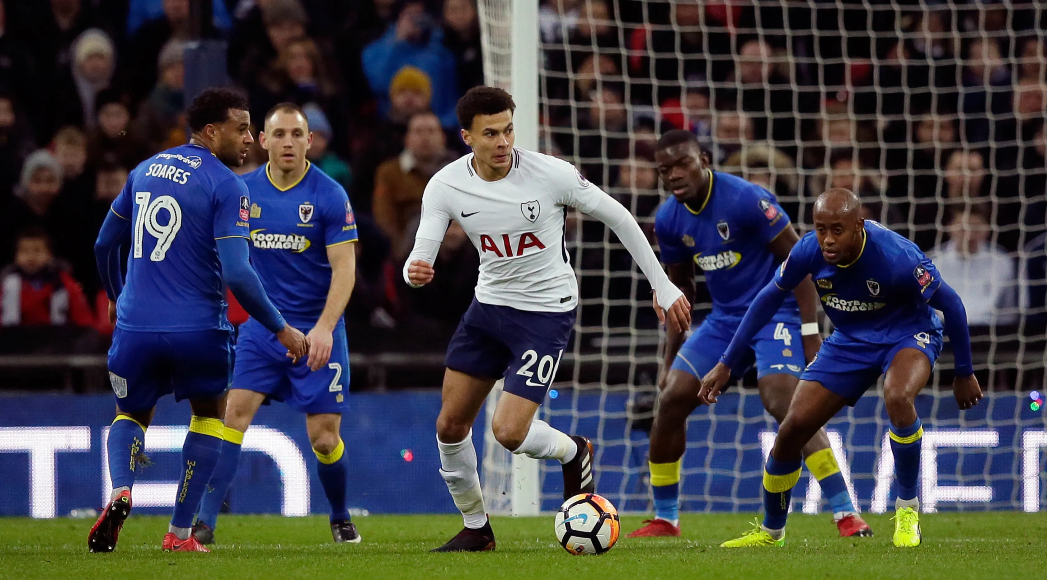 Pemain Tottenham Hotspur, Dele Alli menggiring bola dengan kawalan pemain Wimbledon pada pertandingan putaran ketiga FA Cup di Stadion Wembley, Minggu (7/1). Tottenham Hotspur menyarangkan tiga gol tanpa balas ke gawang Wimbledon. (AP/Tim Ireland)