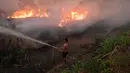 Dengan alat sederhana seorang pemilik perkebunan cabai terus berupaya melindungi lahan miliknya dari kobaran api yang membakar lahan gambut di Ogan Ilir, Sumatra Selatan. Foto diambil pada tanggal 2 Oktober 2023. (Al ZULKIFLI/AFP)