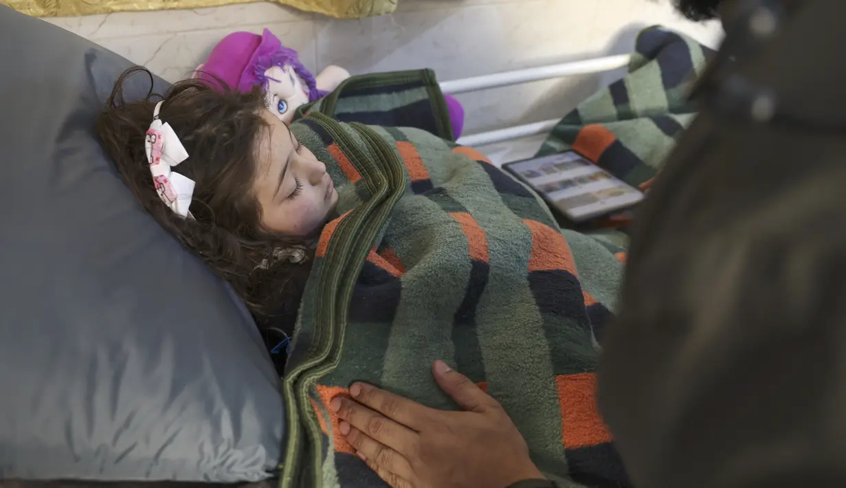 Gadis Suriah Sham Sheikh Mohammad (9) yang diselamatkan setelah empat puluh jam di bawah reruntuhan gempa Turki-Suriah yang mematikan, terbaring di ranjang rumah sakit di provinsi Idlib yang dikuasai pemberontak, pada 17 Februari 2023. Little Sham, seperti banyak orang yang selamat dari gempa berkekuatan M 7,8 yang menewaskan lebih dari 44.000 orang di seluruh Turki dan Suriah pada 6 Februari, sekarang menderita apa yang oleh dokter disebut crush syndrome. (Omar HAJ KADOUR / AFP)