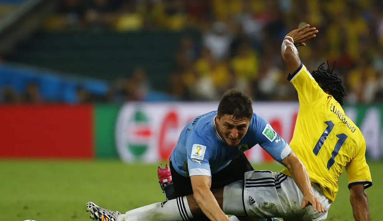 Pemain belakang Uruguay, Diego Lugano (kiri) terjatuh akibat diganjal gelandang Kolombia, Juan Cuadrado, saat berlaga di 16 besar Piala Dunia 2014 di Stadion Maracana, Rio de Janeiro, (29/6/2014). (REUTERS/Kai Pfaffenbach) 