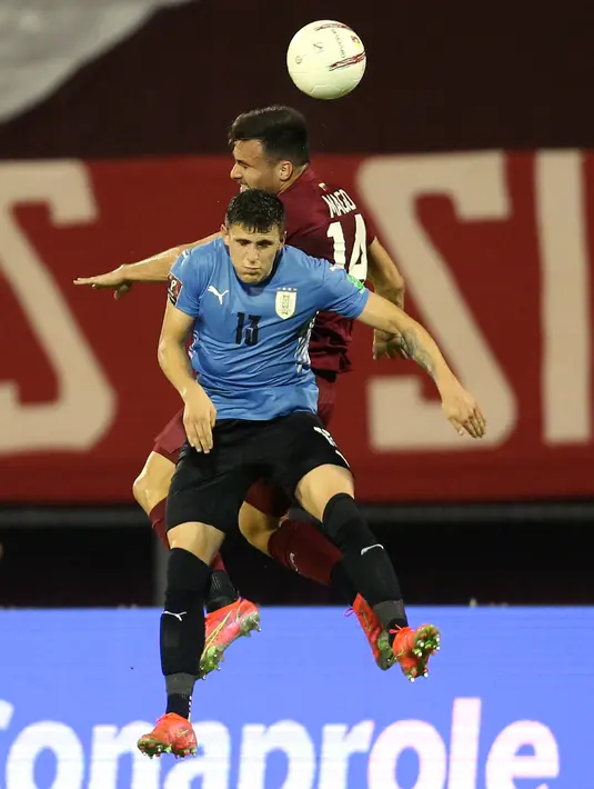Gelandang timnas Uruguay, Federico Valverde (kiri) dan bek Venezuela, Luis Del Pino Mago berebut bola dalam lanjutan kualifikasi Piala Dunia 2022 di Stadion Olimpico de la UCV, Caracas, Rabu (9/6/2021) pagi WIB. Uruguay ditahan imbang tanpa gol oleh Venezuela. (MANAURE QUINTERO/POOL/AFP)