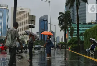 Warga menggunakan payung saat hujan mengguyur kawasan Jakarta, Senin (3/2/2020). Badan Meteorologi, Klimatologi, dan Geofisika (BMKG) merilis informasi peringatan dini cuaca ekstrem yang diperkirakan berlangsung hingga Rabu (5/2/2020) mendatang. (Liputan6.com/Angga Yuniar)