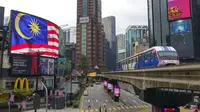 Sebuah LRT (Light Rain Transit) melewati papan bendera Nasional di Kuala Lumpur, Malaysia, Selasa (14/9/2021). Malaysia pecah rekor tembus dua juta kasus Covid-19 dengan tambahan 15.669 kasus Selasa (14/9/2021). (AP Photo/Vincent Thian)