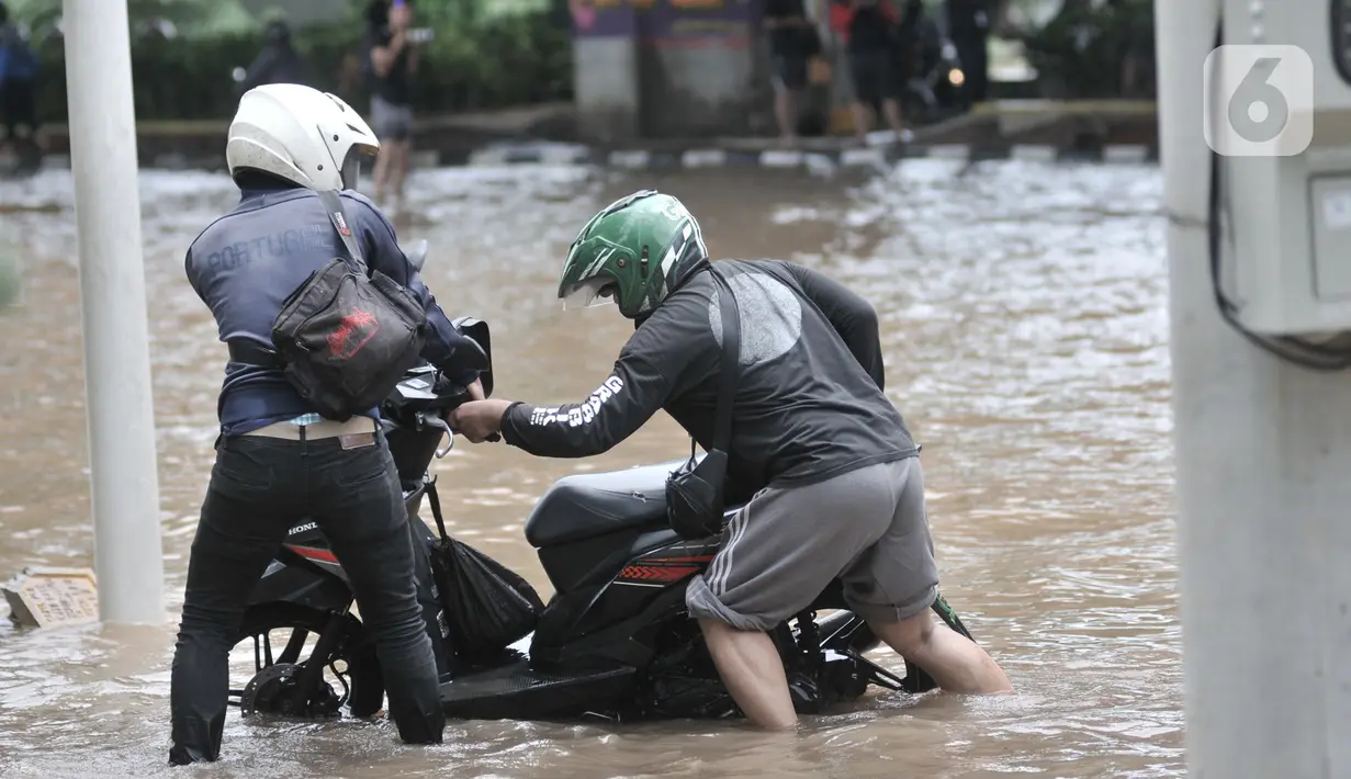 Warga mendorong sepeda motor setelah mogok akibat nekat menerobos banjir di Jalan Ahmad Yani, Jakarta, Minggu (23/2/2020). Kondisi banjir yang lama surut memaksa pengendara motor nekat menerobos, namun kebanyakan dari mereka mengalami mogok. (merdeka.com/Iqbal S. Nugroho)