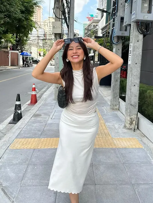 Gaya liburan yang chic dari Tyna Dwi Jayanti pakai outfit serba putih. Ia memadukan atasan silk tanpa lengan dan rok midi yang juga dari bahan yang sama. [Foto: Instagram/tynadwijayanti]