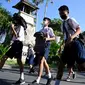 Anak-anak sekolah menggunakan tas mereka untuk melindungi diri saat latihan gempa dan tsunami di Tanjung Benoa, Kabupaten Badung, Bali, 24 Mei 2022. (SONY TUMBELAKA/AFP)