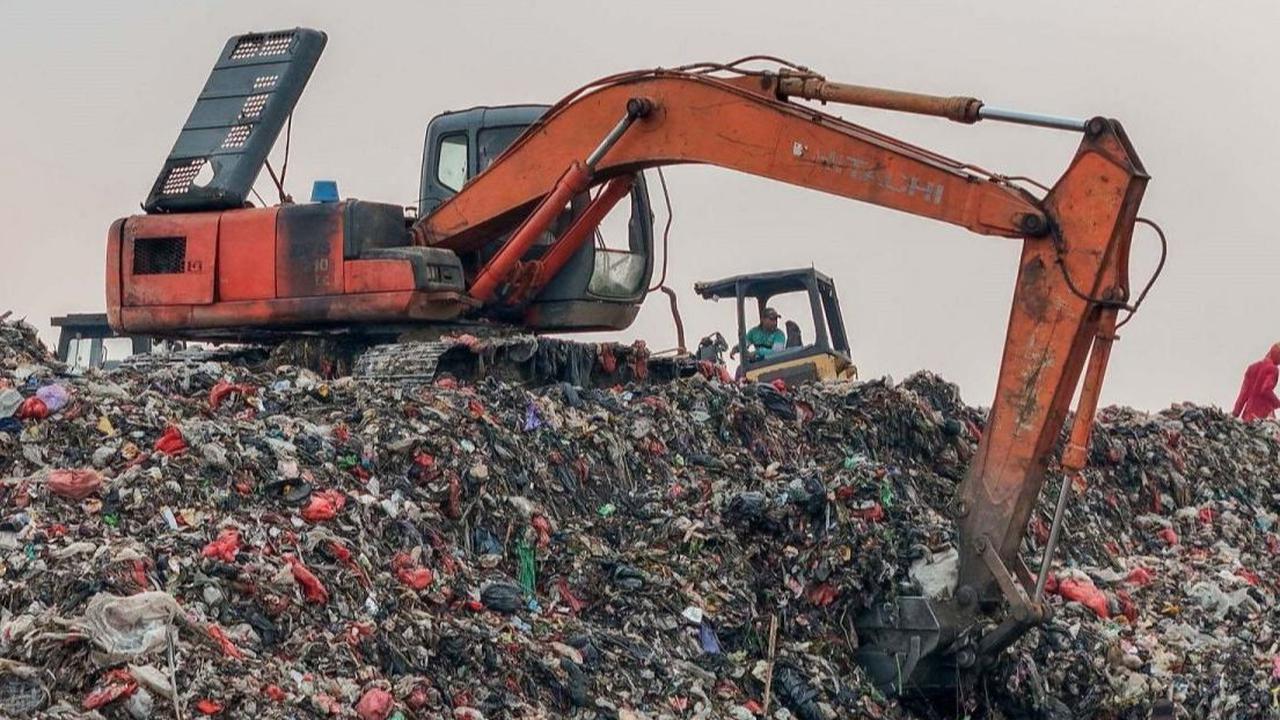 Sebuah alat berat eskavator beroperasi untuk mengurangi tumpukan sampah yang menggunung di lokasi pembuangan sampah TPA Cipayung, Depok, Jawa Barat, Selasa (07/5/2024). Foto: merdeka.com / Arie Basuki