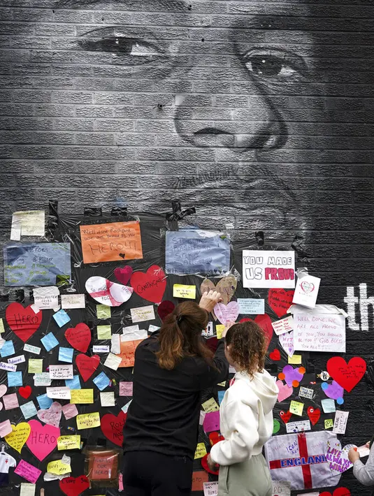 Orang-orang menempatkan pesan dukungan di mural Marcus Rashford yang dirusak di Withington, Manchester (12/7/2021). PM Inggris Boris Johnson mengutuk pelecehan rasis kepada tiga pemain Black England yang gagal mengeksekusi penalti melawan Italia di final Euro 2020. (Peter Byrne/PA via AP)