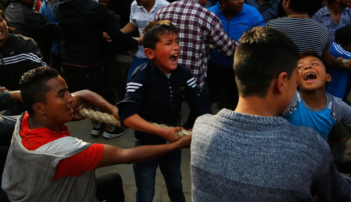Ekspresi seorang anak saat ikut menarik kereta kayu dewa Bhairava dalam festival Bisket Jatra di Bhaktapur, Nepal (10/4). Mereka menarik kereta kayu yang membawa dewa Hindu Bhairava ke lapangan terbuka. (AP Photo/Niranjan Shrestha)
