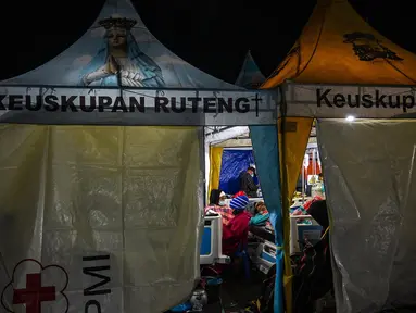 Kerabat menyaksikan para korban gempa bumi mendapatkan perawatan di tenda medis darurat di depan Rumah Sakit Ruteng di Ruteng, Manggarai, Nusa Tenggara Timur, Sabtu malam, 15 Agustus 2025. (AFP/ Juni Kriswanto)