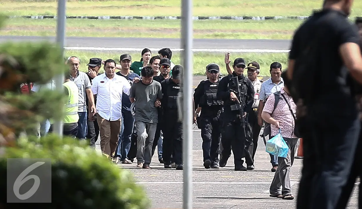 Petugas kepolisian membawa tersangka pembunuhan dan perampokan Pulomas Ridwan Sitorus saat tiba di Bandara Halim Perdana Kusuma, Jakarta, Minggu (1/1). (Liputan6.com/Faizal Fanani)