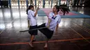 Dua siswi bertarung menggunakan pedang selama berlatih Krabi Krabong di sekolah Thonburee Woratapeepalarak, Thonburi, Bangkok (8/7/2019). Krabi Krabong merupakan seni bela diri Thailand yang dipersenjatai pisau dan perisai kayu. (AFP Photo/Lillian Suwanrumpha)