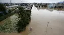 Seorang pria berjalan di luapan banjir dari Sungai Kinugawa di Joso, prefektur Ibaraki, Jepang, Kamis (10/9). Banjir yang disebabkan topan Etau ini mengakibatkan satu orang hilang dan 90 ribu lebih warga diperintahkan untuk mengungsi. (REUTERS/Issei Kato)