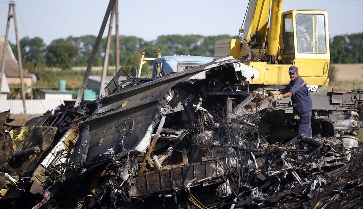 Salah satu anggota Kementerian Darurat Ukraina berusaha memindahkan serpihan puing pesawat MH-17 yang jatuh di desa Hrabove, Donetsk, Ukraina, (20/7/2014). (REUTERS/Maxim Zmeyev)
