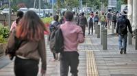 Pegawai pulang kerja berjalan di trotoar Jalan Sudirman, Jakarta, Selasa (12/5/2020). Pemerintah memberi kelonggaran bergerak bagi warga berusia di bawah 45 tahun untuk mengurangi angka pemutusan hubungan kerja (PHK) akibat pandemi virus corona COVID-19. (Liputan6.com/Johan Tallo)