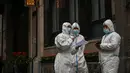 Pekerja yang mengenakan alat pelindung diri berdiri di sebelah akses hotel di Bund, Puxi, Shanghai, China, 31 Maret 2022. Daerah Puxi akan lockdown mulai 1 April 2022. (Hector RETAMAL/AFP)