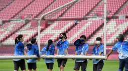 Relawan membawa tiang gawang sebelum pertandingan sepak bola putaran pertama grup G putri Olimpiade Tokyo 2020 antara AS dan Australia di Stadion Ibaraki Kashima di kota Kashima, pada 27 Juli 2021. Relawan atau volunteer merupakan salah satu kunci suksesnya suatu perhelatan. (SHINJI AKAGI/AFP)