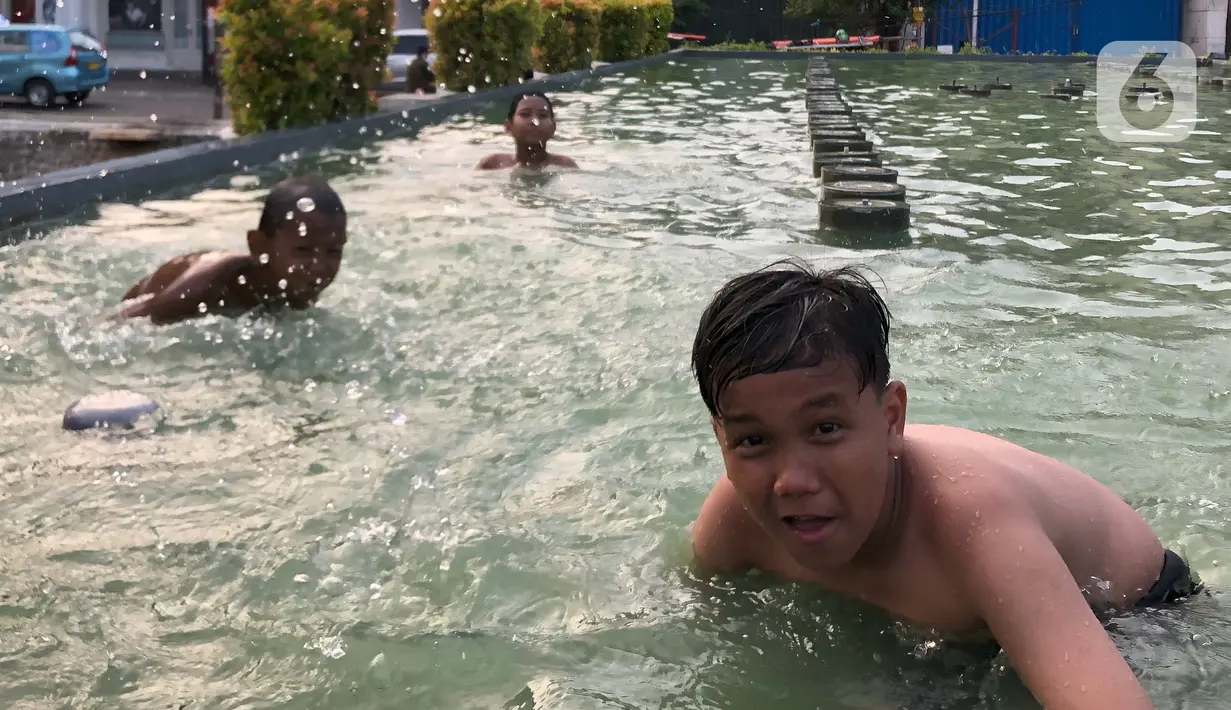 Keseruan anak-anak berenang di kolam penghias taman Pasar Baru di Jakarta, Rabu (2/9/2020). Meskipun terdapat larangan, namun sejumlah anak tetap nekat berenang di kolam tersebut sehingga mengganggu ketertiban umum. (Liputan6.com/Immanuel Antonius)