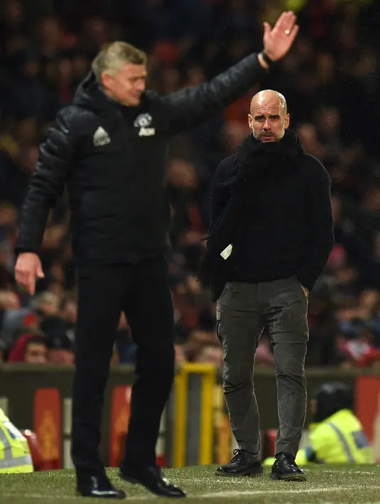 Pelatih Manchester City Pep Guardiola (kanan) dan manajer Manchester United Ole Gunnar Solskjaer saat menyaksikan para pemain mereka bertanding pada laga Liga Inggris di Old Trafford, Manchester, Inggris, Minggu (8/3/2020). Manchester United menang 2-0. (Oli SCARFF/AFP)