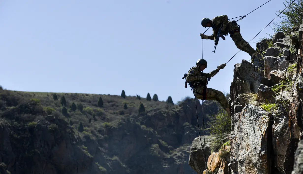 Pasukan menuruni tebing saat ikut serta dalam latihan gabungan Kyrgyzstan dan India di Ngarai Tatyr, selatan Bishkek, dekat Desa Arashan, Kyrgyzstan, Senin (26/4/2021). Pasukan tersebut berlatih untuk mengoordinasikan aksi mereka melawan militan. (AP Photo/Vladimir Voronin)