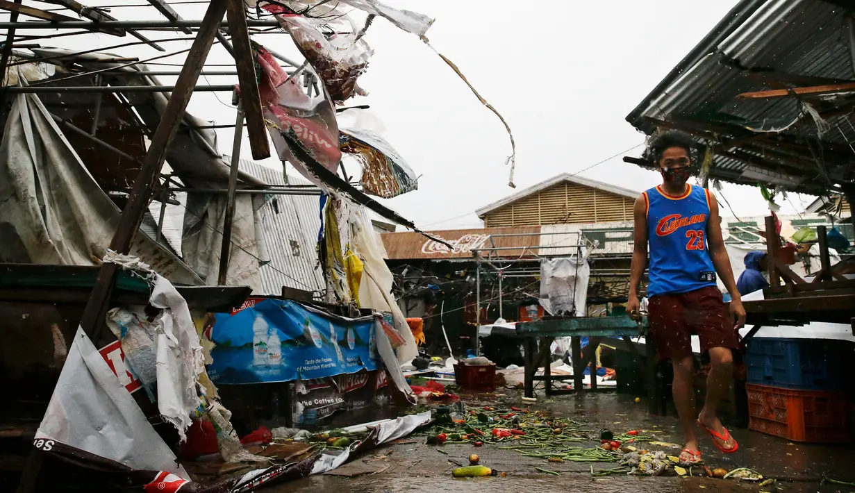 Warga berjalan di samping bangunan yang roboh akibat Topan Mangkhut di kota Tuguegarao di provinsi Cagayan, timur laut Filipina (15/9). (AP Photo/Aaron Favila)
