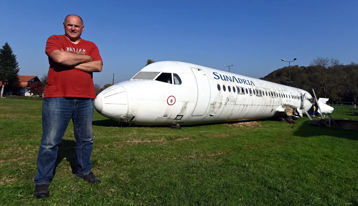 Robert Sedlar (50) berpose di depan pesawat Fokker-100 yang diparkir di halaman rumahnya di Strmec Stubicki, dekat Zagreb, Kroasia, 26 Oktober 2019. Keberadaan pesawat menjadi pemandangan unik di Desa Strmec Stubicki yang berada di tengah perbukitan nan indah. (Denis LOVROVIC / AFP)