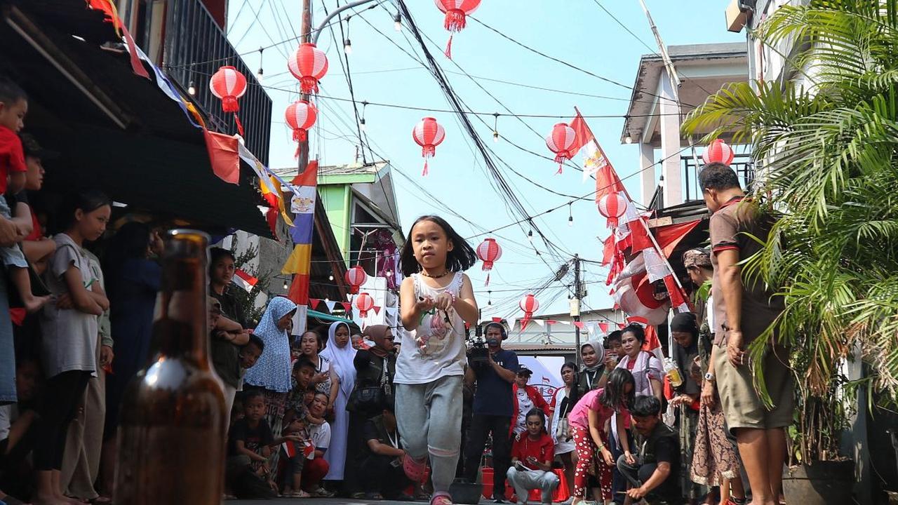 Seorang anak berusaha berlari saat akan memasukkan tubuh belut yang licin ke dalam botol.