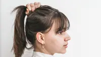 Ilustrasi rambut dikuncir tinggi. (Photo by Scandinavian Biolabs: https://www.pexels.com/photo/woman-in-white-top-holding-hair-to-ponytail-8466562/)