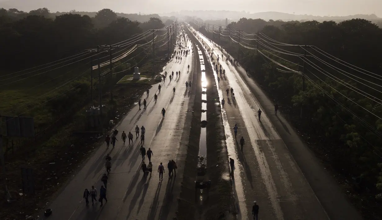 Komuter berjalan di sepanjang Pan American Highway akibat penghalang jalan yang dibuat oleh pengunjuk rasa yang berdemonstrasi menentang inflasi, terutama kenaikan harga bahan bakar, di Pacora, Panama, Rabu pagi (20/7/2022). Protes minggu ketiga dan blokade jalan raya mulai berdampak pada pasokan makanan dan barang-barang lainnya di beberapa bagian Panama. (AP Photo/Arnulfo Franco)
