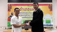 Salah seorang remaja, Adul Samon menerima kartu identitas sebagai warga negara Thailand di distrik Mae Sai, Rabu (8/8). Korban gua Thailand tersebut selama ini hidup tanpa memiliki status kewarganegaraan. (Chiang Rai Public Relations Office via AP)