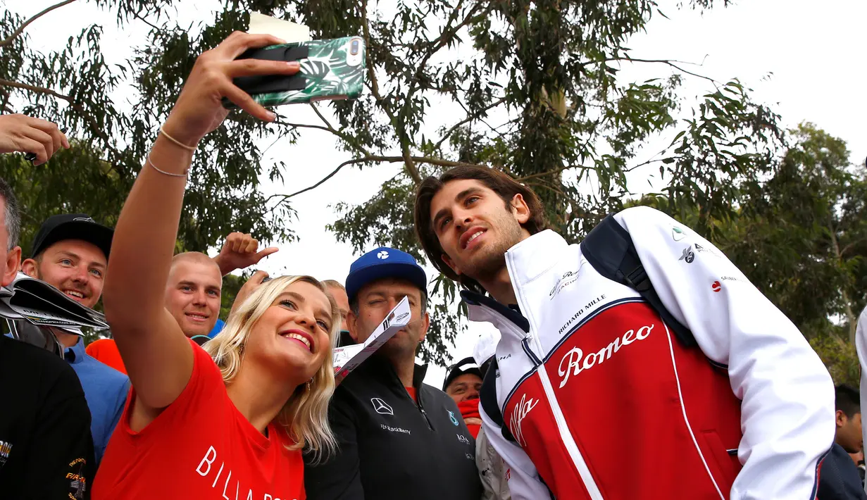 Pembalap F1 Alfa Romeo, Antonio Giovinazzi berselfie bersama penggemarnya saat tiba di Sirkuit Melbourne Grand Prix di Melbourne, Jumat (15/3). (Reuters/Edgar Su)
