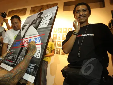 Drummer grup musik Superman Is Dead, Jrx (kiri) menandatangani foto saat pameran fotografi "Laut Luka Blues" di Galeri Foto Jurnalistik Antara , Jakarta, Jumat (22/5/2015). 51 karya foto karya Ismar Patrizki dipamerkan. (Liputan6.com/Faizal Fanani)