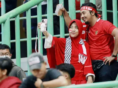 Suporter melakukan swafoto usai memberi dukungan saat Timnas Indonesia U-19 melawan Brunei Darussalam pada laga kedua Grup A Piala AFF U-19 2022 di Stadion Patriot Candrabhaga, Bekasi, Senin (4/7/2022). (Bola.com/M Iqbal Ichsan)