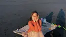 Atau potret manis Pevita saat menikmati waktu santai di pinggir pantai. Ia duduk di atas kain mengenakan outfit berwarna oranye. [Foto: Instagram/pevpearce]