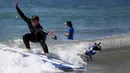 Seorang pria bersama anjingnya beraksi saat mengikuti Surf Dog Contest Surf City di Huntington Beach, California, Amerika Serikat, (27/9/2015). (REUTERS/Lucy Nicholson)